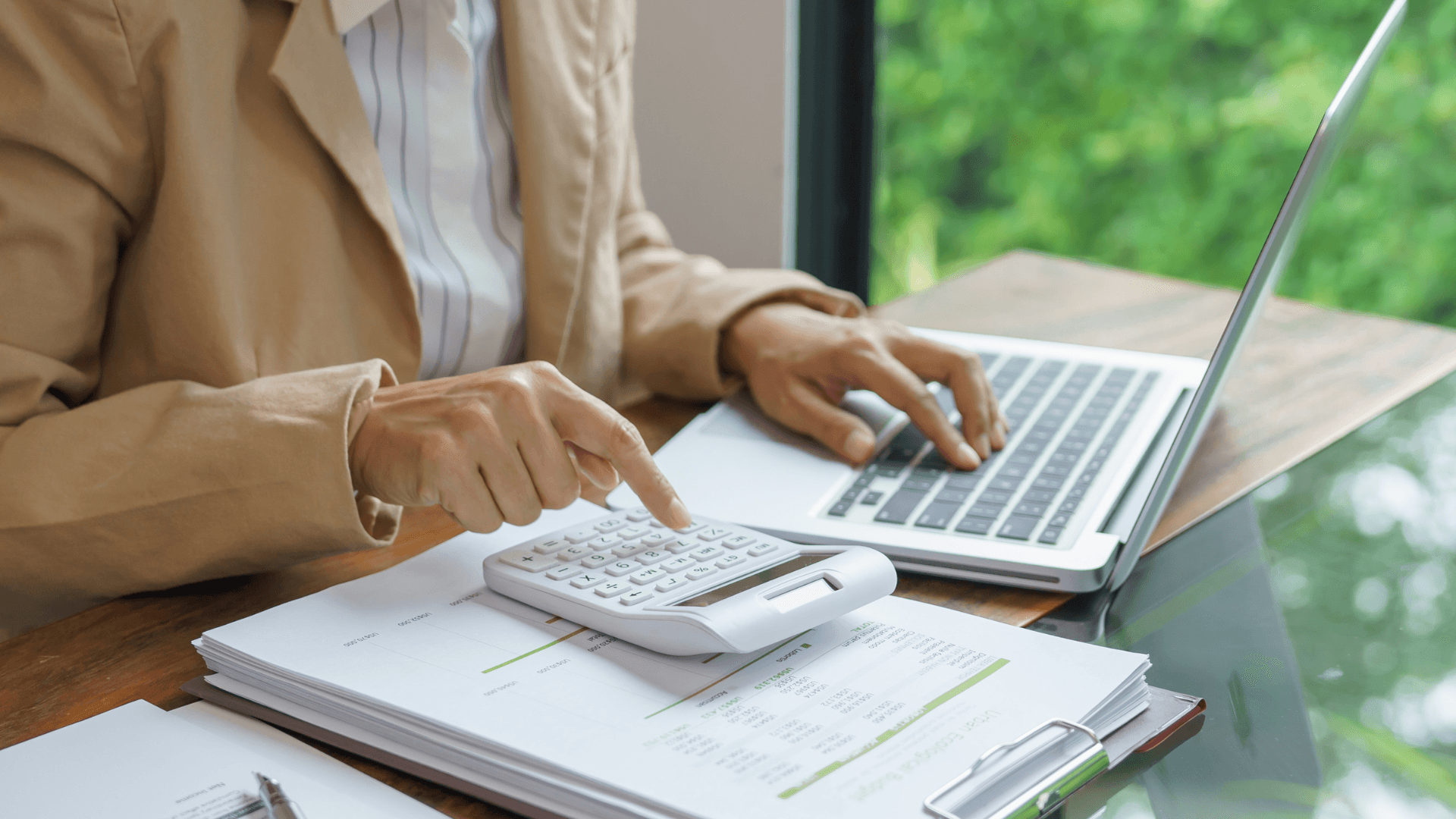 Image of a person working with a calculator and a laptop