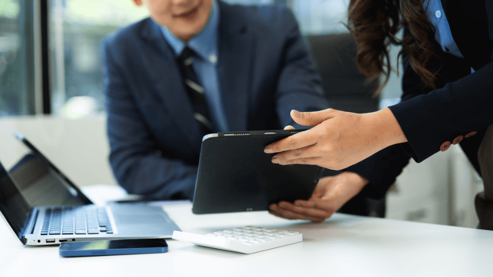 Image of female office working showing her male college something on her tablet